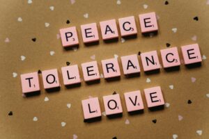 Pink tiles on a polka dot background spelling peace, tolerance, and love.