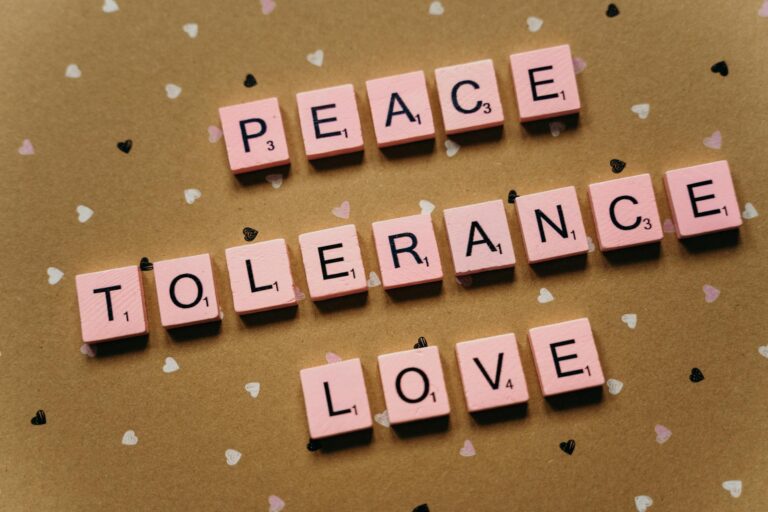 Pink tiles on a polka dot background spelling peace, tolerance, and love.