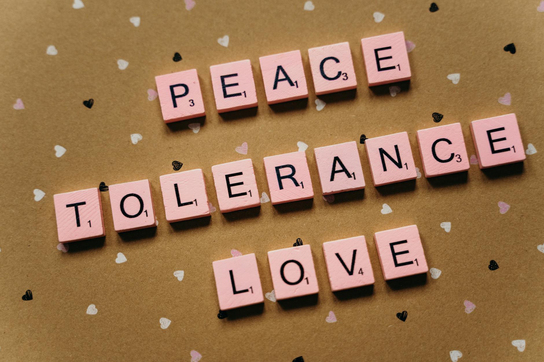 Pink tiles on a polka dot background spelling peace, tolerance, and love.